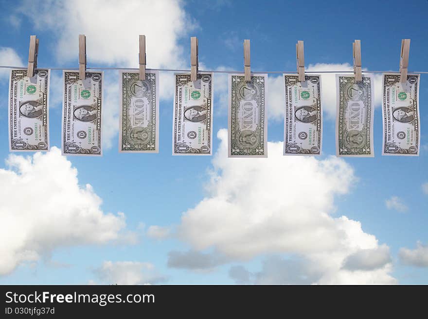 1 dollar bills hanging on a clothes line with clouds on background. 1 dollar bills hanging on a clothes line with clouds on background