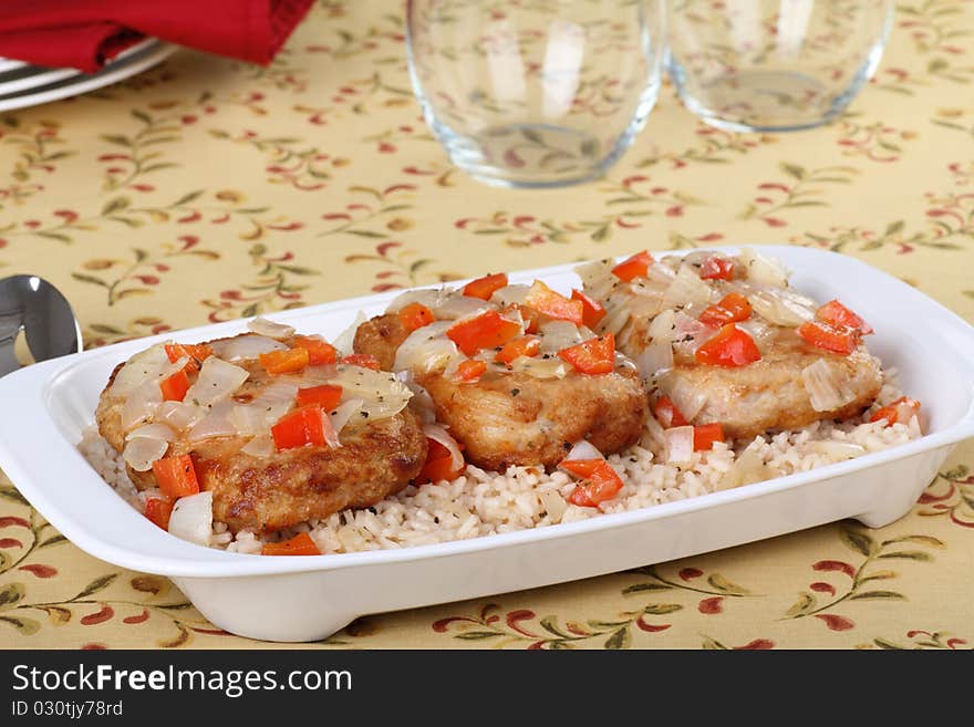 Pork cutlet meal topped with red peppers and onions with rice on a platter