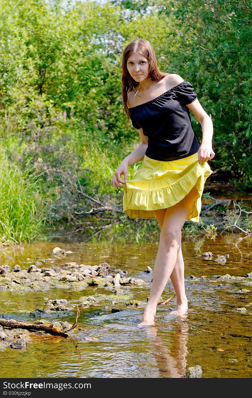 Young woman crossing little stream in forest. Young woman crossing little stream in forest