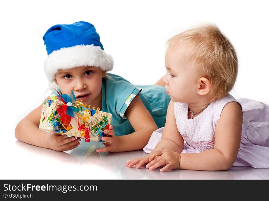 Girl in Santa's blue hat giving out a present to a baby isolated on white. Girl in Santa's blue hat giving out a present to a baby isolated on white