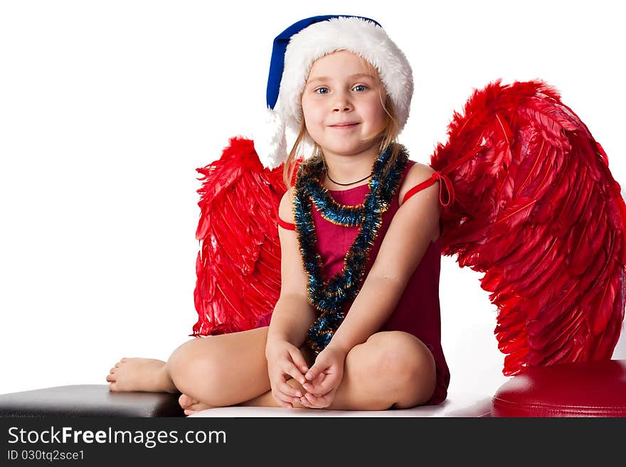 Girl in Santa'sblue hat and tinsel with red angel's wings isolated on white. Girl in Santa'sblue hat and tinsel with red angel's wings isolated on white