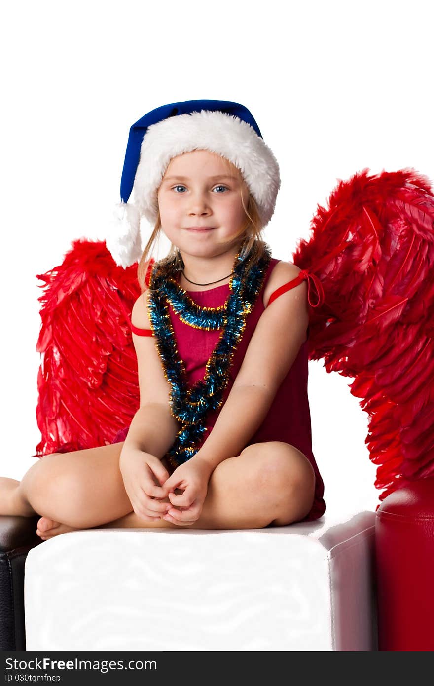 Girl in Santa's blue hat and tinsel with red angel's wings  isolated on white. Girl in Santa's blue hat and tinsel with red angel's wings  isolated on white