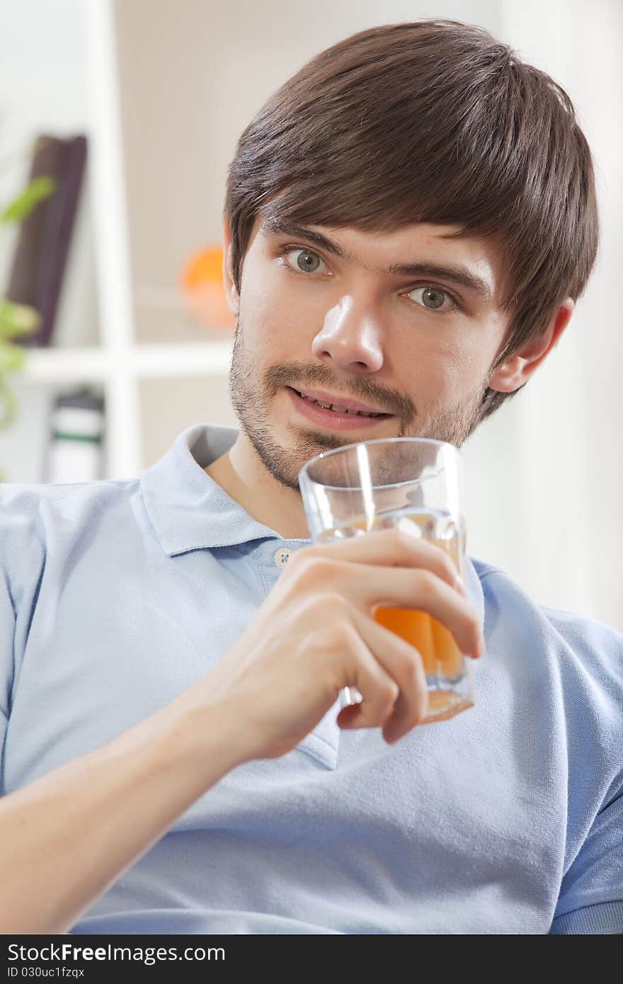 Young man holding glass juice on the sofa at home. Young man holding glass juice on the sofa at home