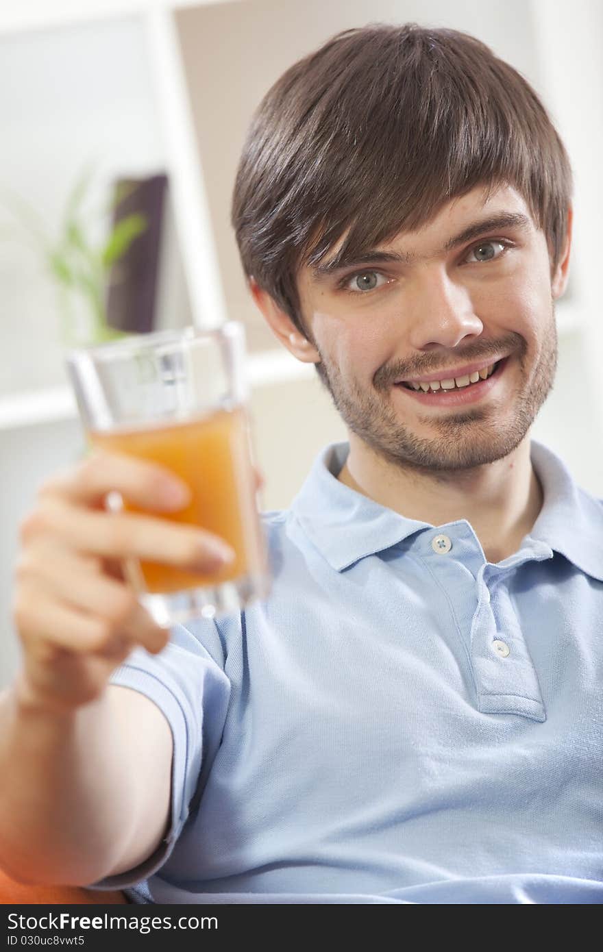 Happy man holding glass orange juice in his hand at home. Happy man holding glass orange juice in his hand at home