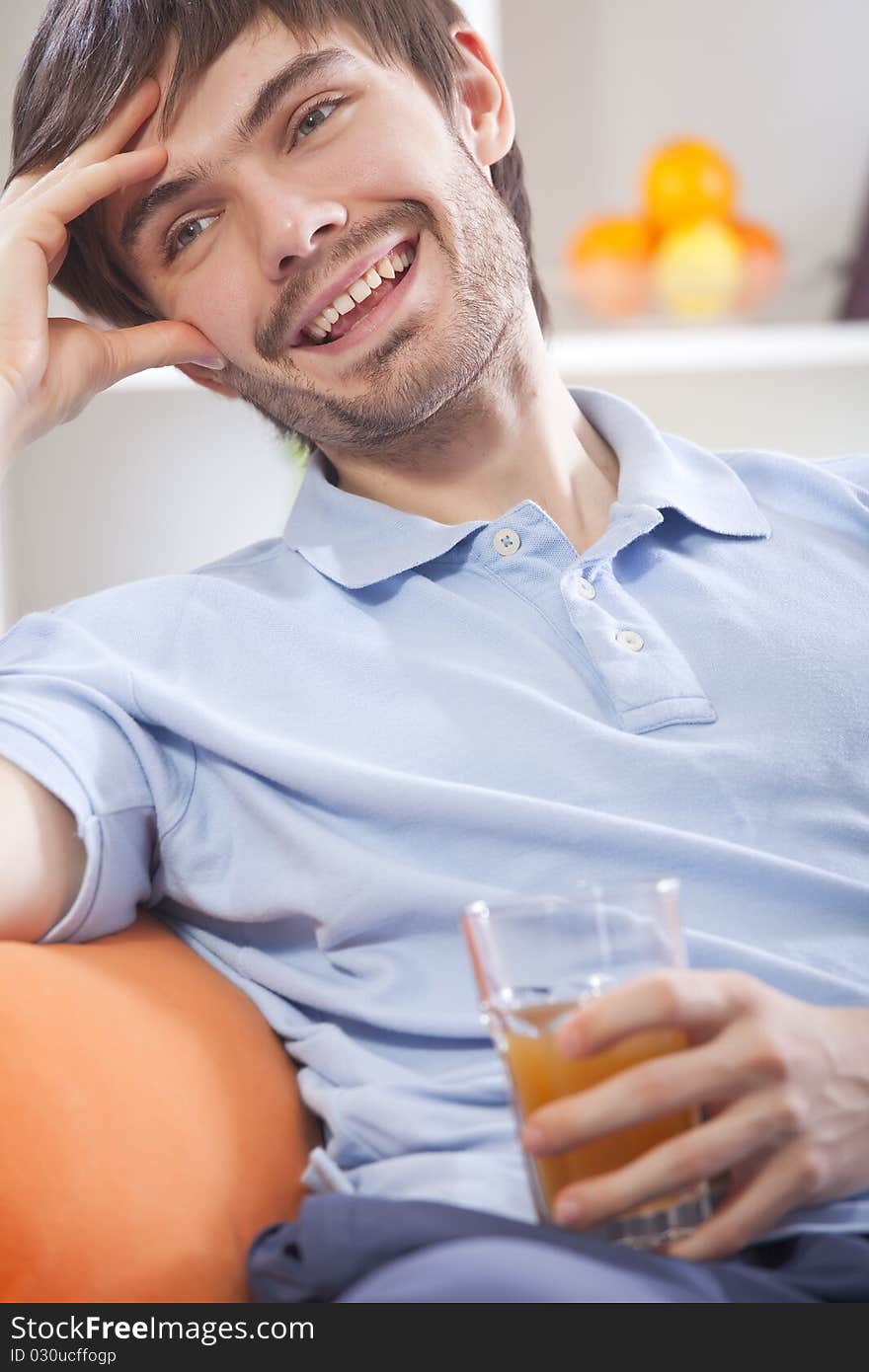 Attractive young man drinking orange juice at home