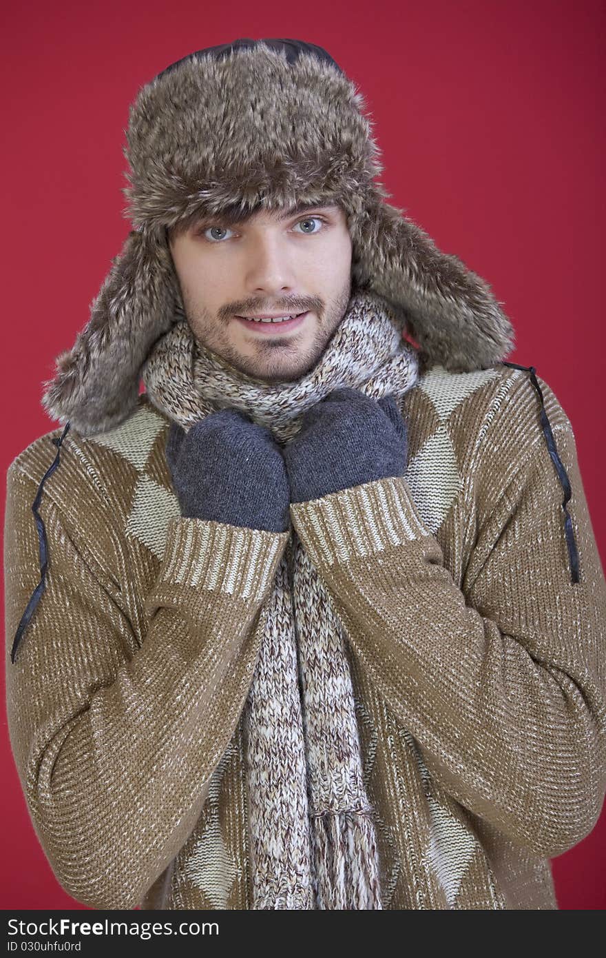 Portrait of happy man in fur hat, gloves and knit scarf over red background. Portrait of happy man in fur hat, gloves and knit scarf over red background