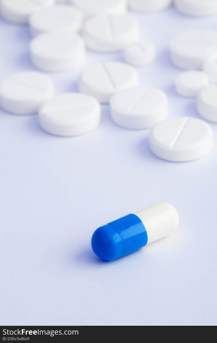 Tablets od different sizes on a white background and capsule on foreground. Tablets od different sizes on a white background and capsule on foreground