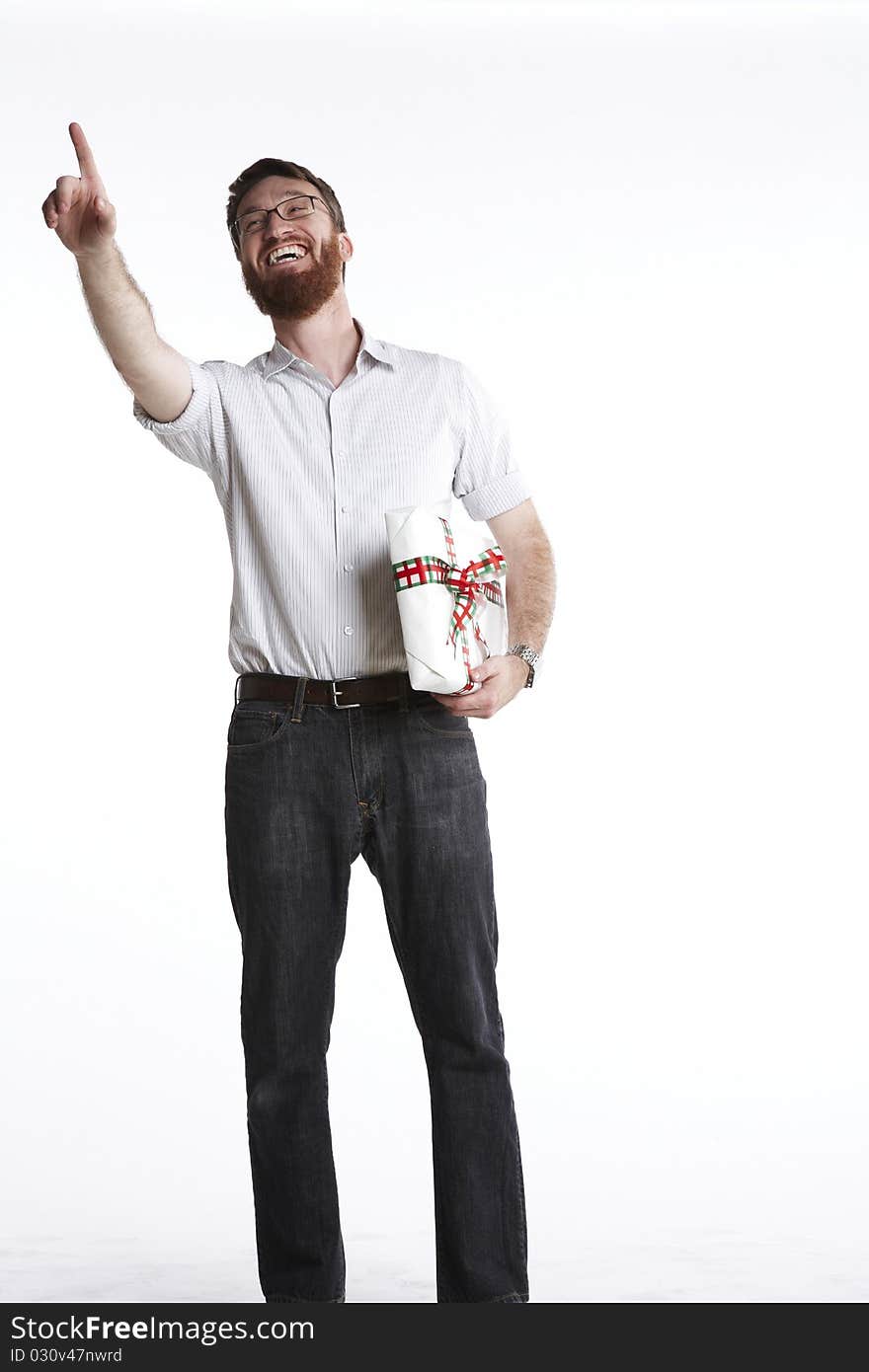 Man pointing to someone out of frame and smiling while holding a wrapped present. Man pointing to someone out of frame and smiling while holding a wrapped present