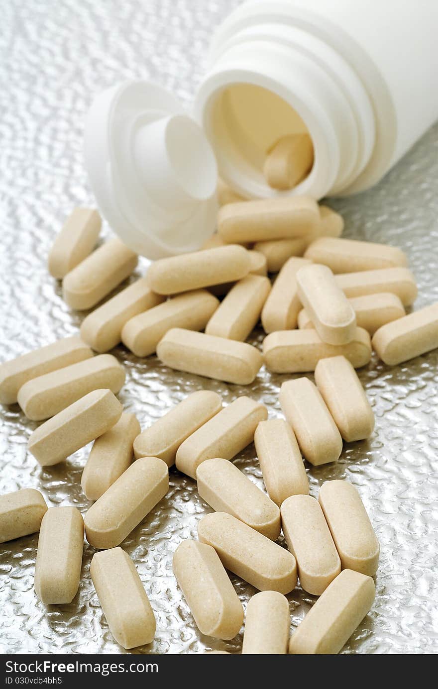 Pills being poured on a metal plate from a container overturned