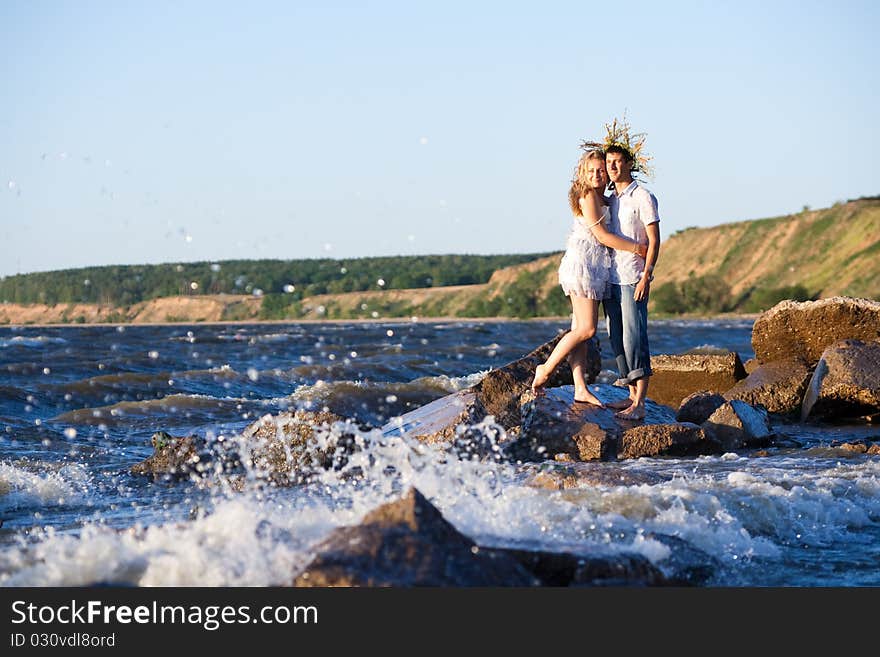 Pair enamoured on river bank look at a surf. Pair enamoured on river bank look at a surf