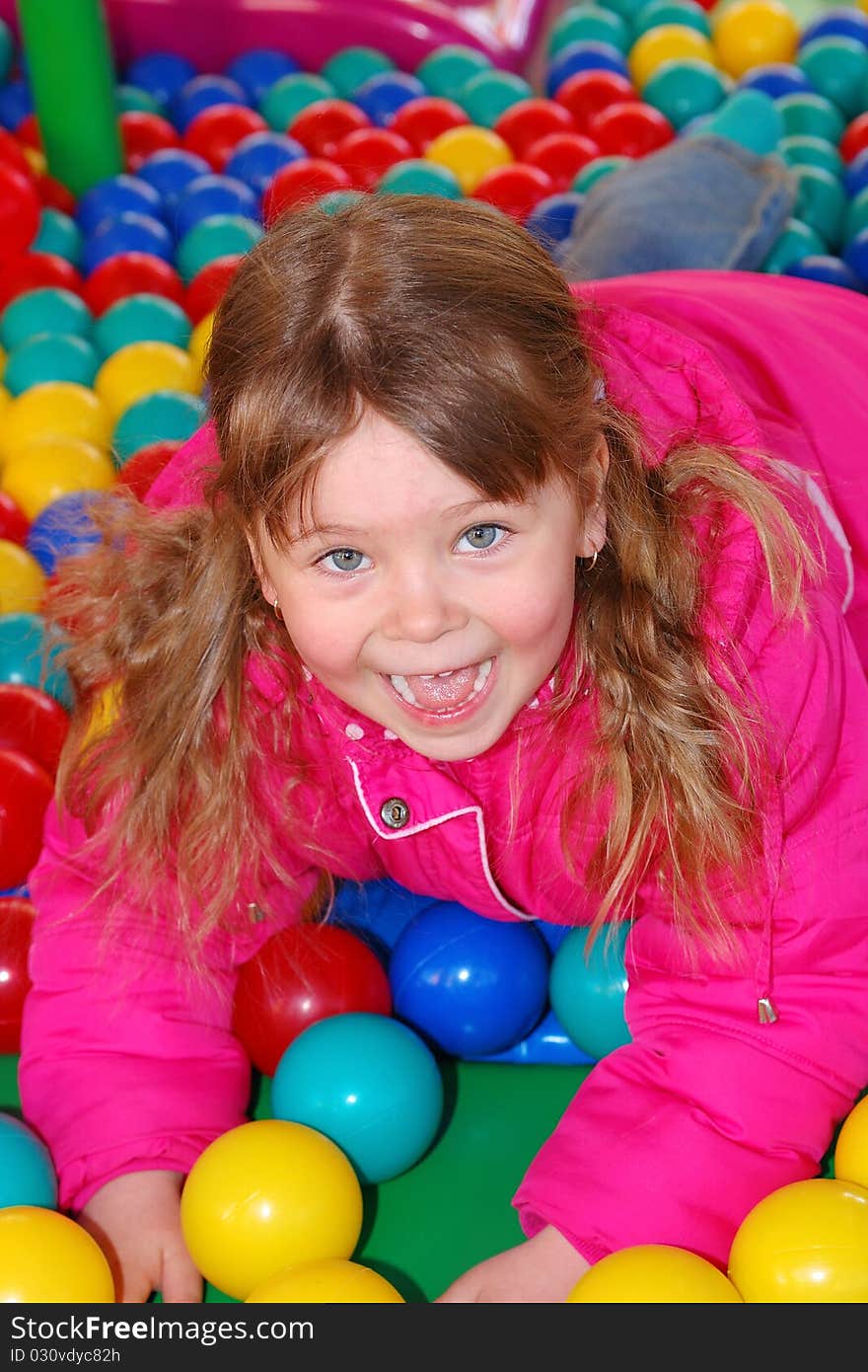 The girl lies on multicolored spheres in a children's attraction