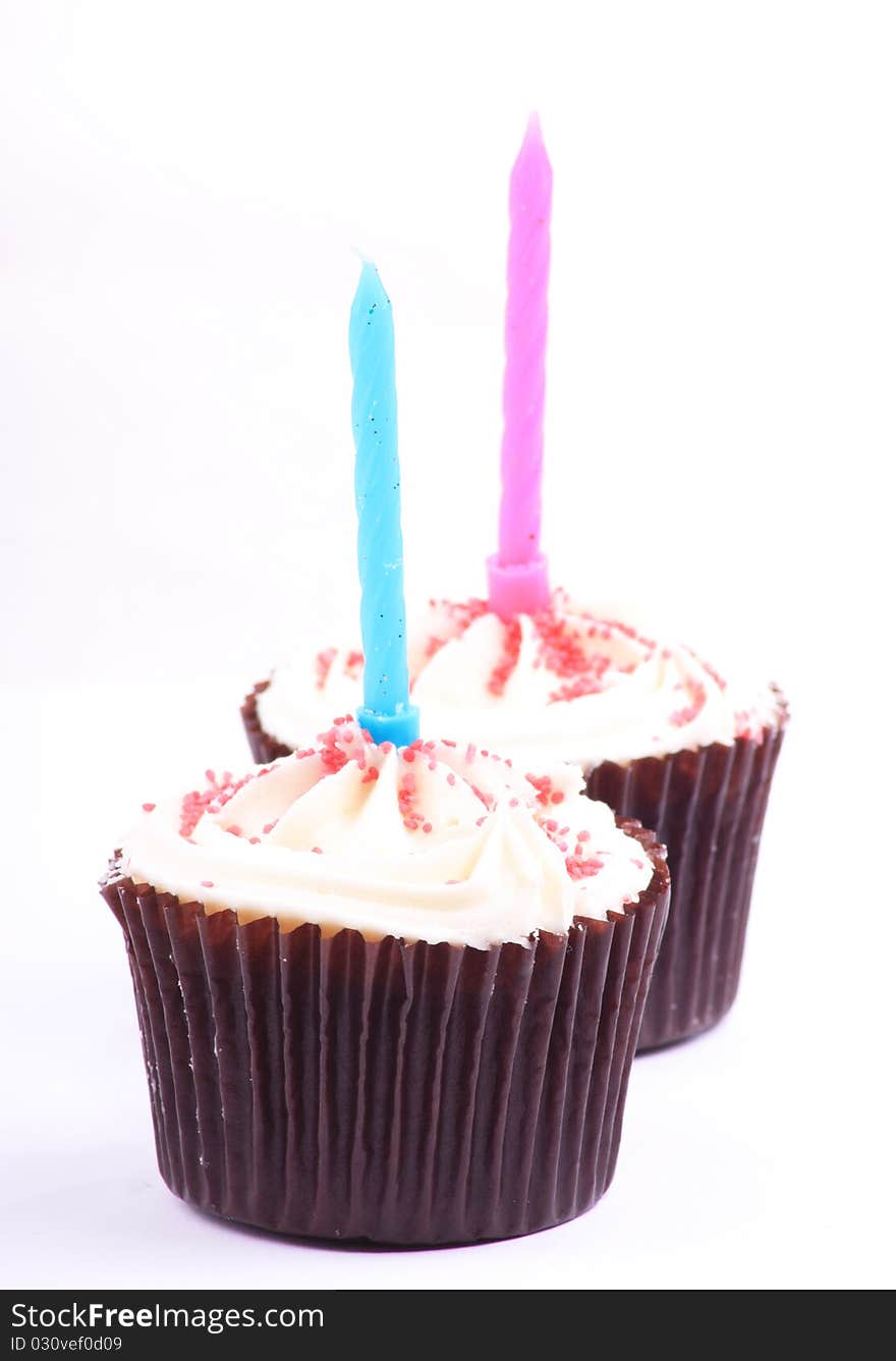 Two lovely looking caked on a white background with a pink and blue candle in them. Two lovely looking caked on a white background with a pink and blue candle in them