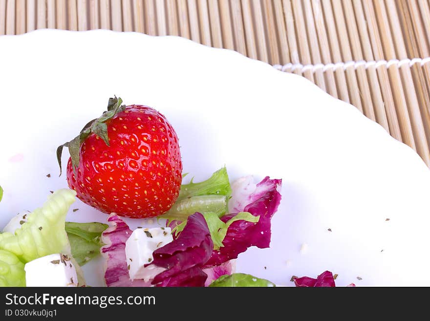 Strawberry and salad on plate, closed-up