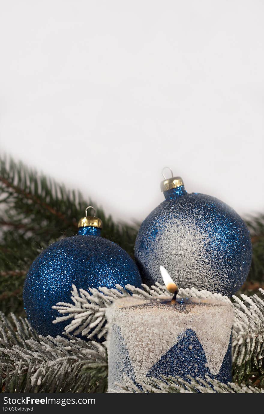 Christmas decoration, blue christmas balls and burning candle on spruce branch