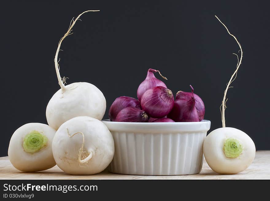 Four green tupnips with red pearl onions on the table