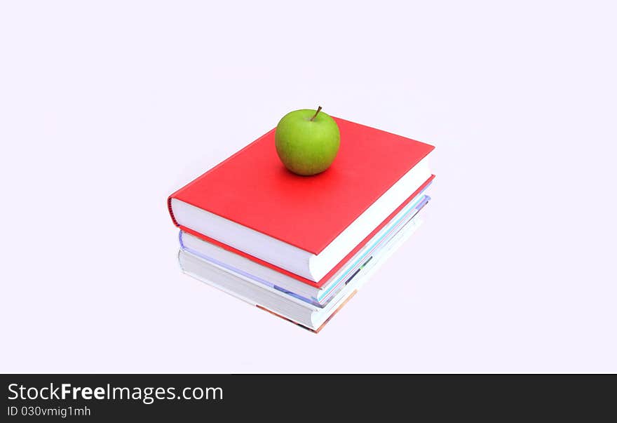 A stack of books with a green apple on top ready for lunch after study. A stack of books with a green apple on top ready for lunch after study