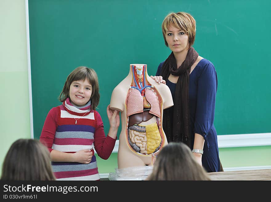 Happy children group in school classrom taking notes and learning biology and anatomy lessons with teacher. Happy children group in school classrom taking notes and learning biology and anatomy lessons with teacher