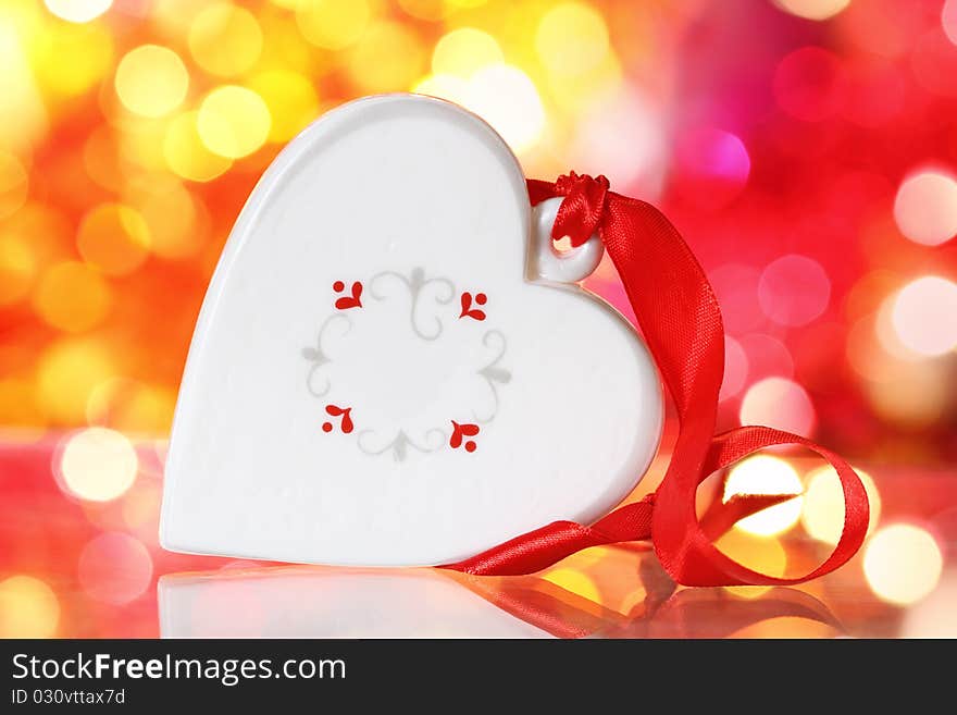 Christmas white heart with red ribbon against blurred background