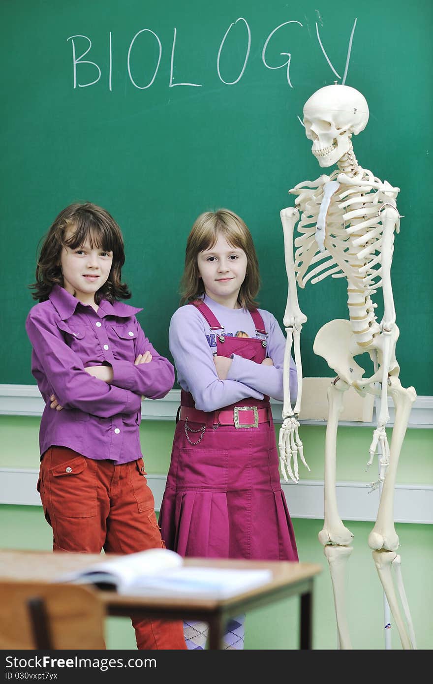 Happy children group in school classrom taking notes and learning biology and anatomy lessons with teacher. Happy children group in school classrom taking notes and learning biology and anatomy lessons with teacher