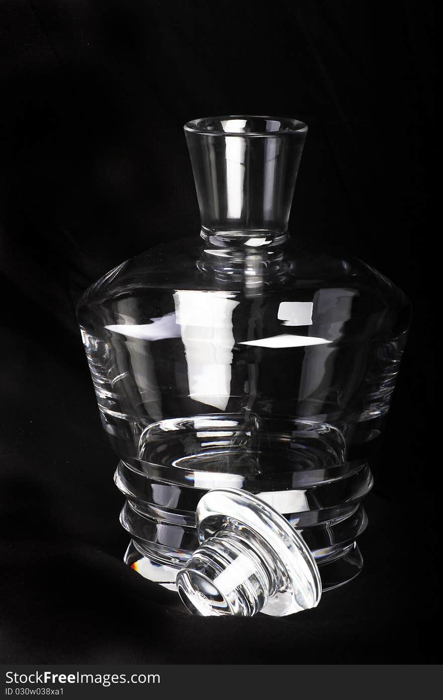 Empty crystal decanter with the lid next to it and black background. Empty crystal decanter with the lid next to it and black background