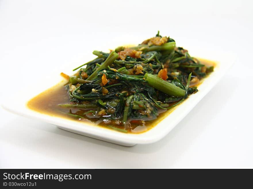 Asian style fried vegetable with shrimps served in white plate with white background.