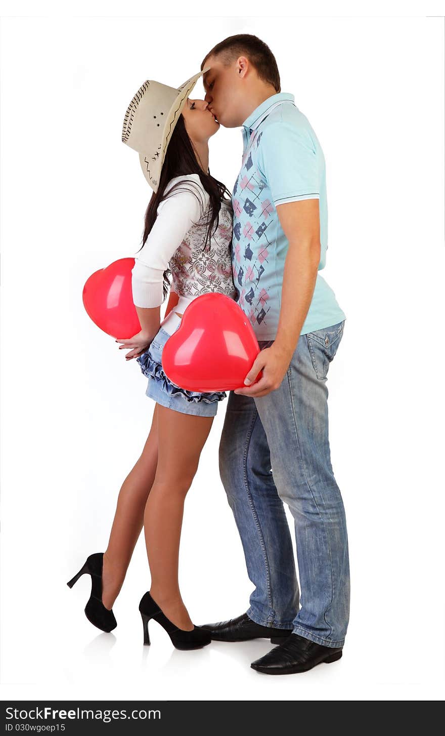 The beautiful high guy and the fine girl in a cowboy's hat embraces and kisses a balloon. The beautiful high guy and the fine girl in a cowboy's hat embraces and kisses a balloon