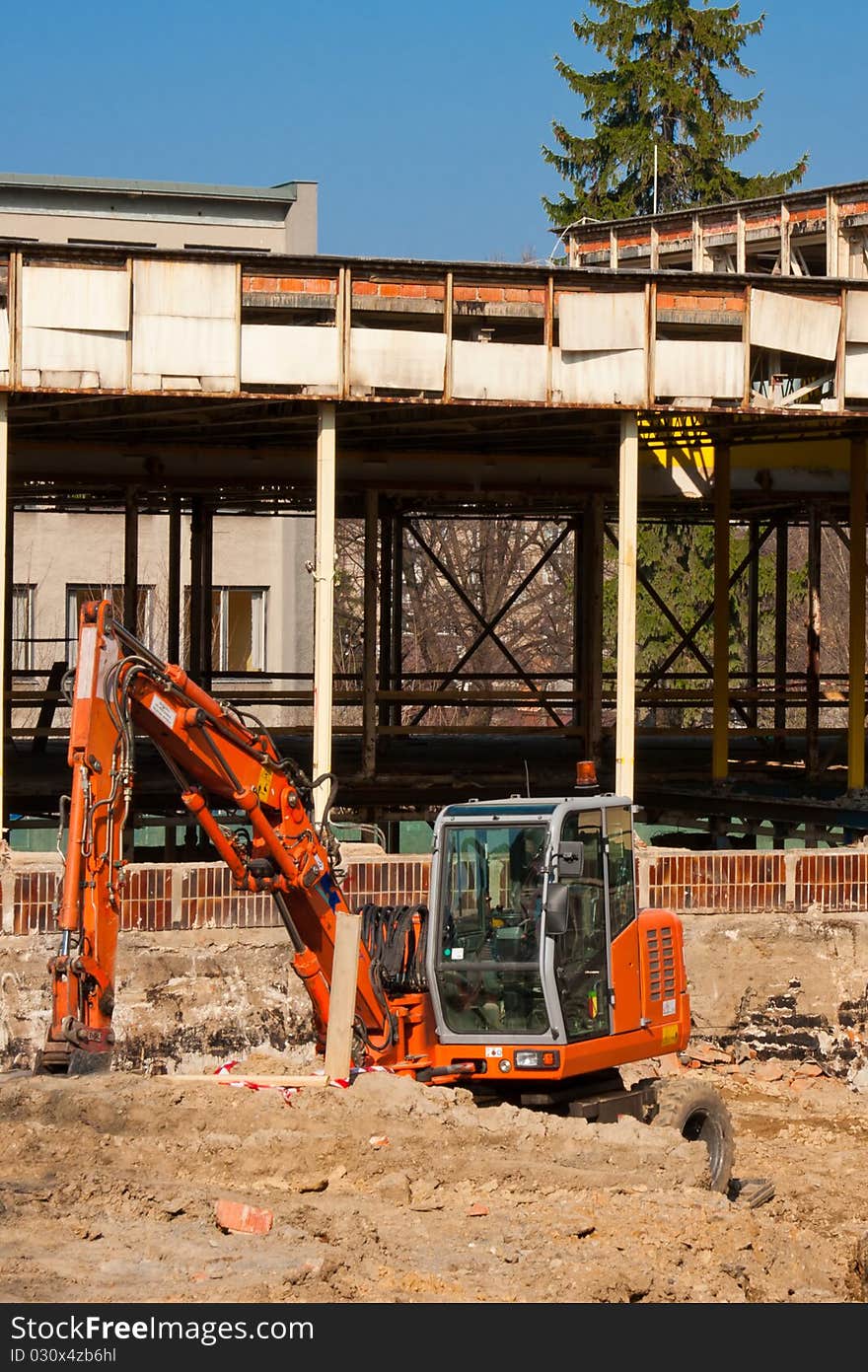 Small orange excavator on construction site