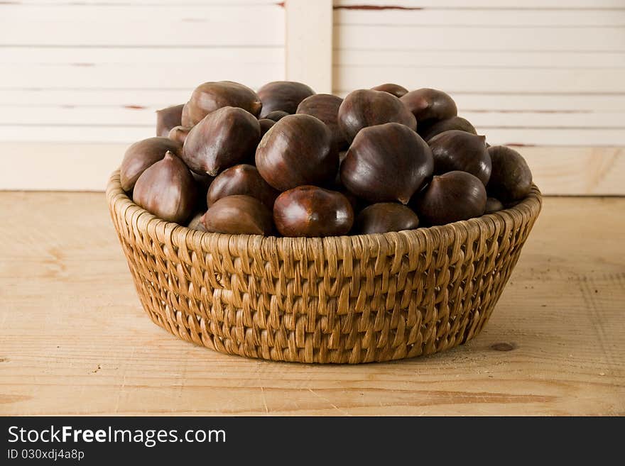 Chestnuts basket isolated on a wooden table, horizontal version