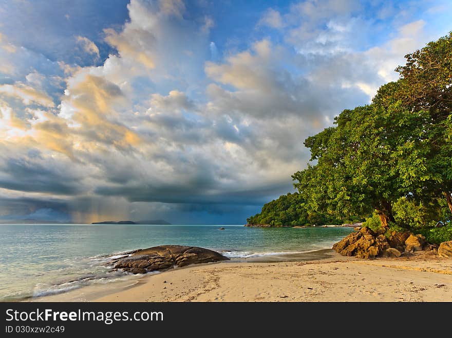 Thunder storm approaching the tropical beach lit by sun. Thunder storm approaching the tropical beach lit by sun