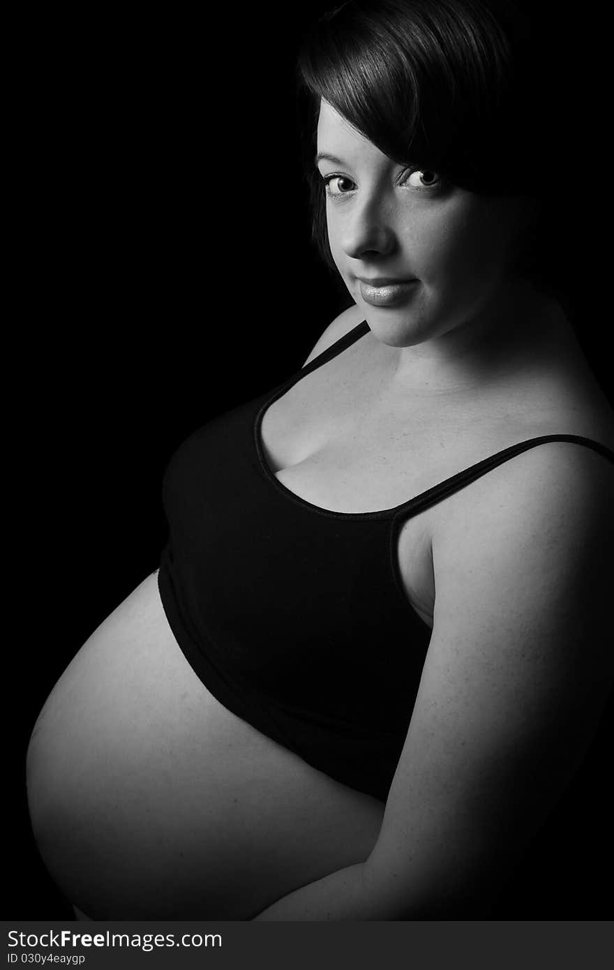 Pregnant women with bare belly on black background. Pregnant women with bare belly on black background