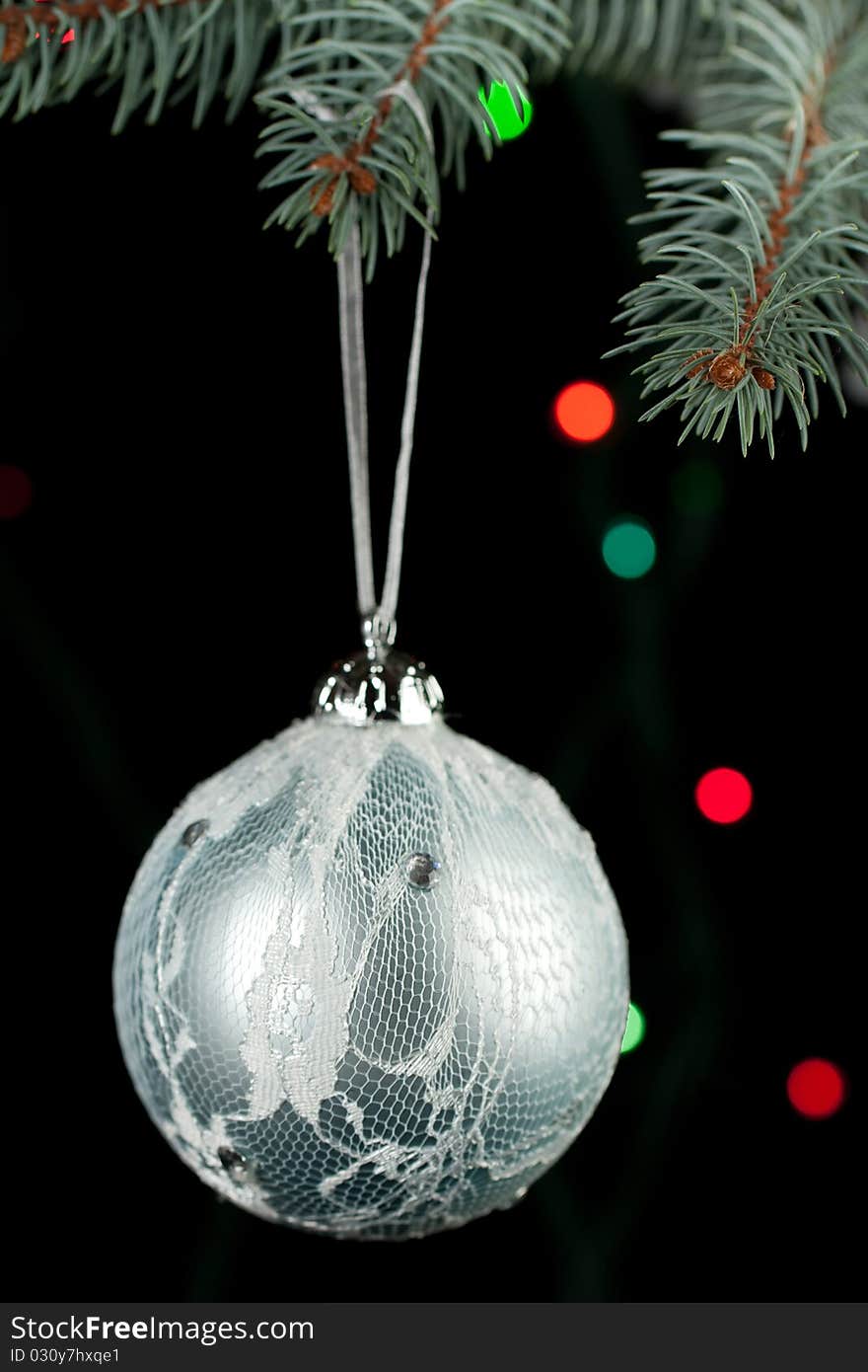 Silver christmas ball on a christmas tree on the black background and colorful light. Silver christmas ball on a christmas tree on the black background and colorful light