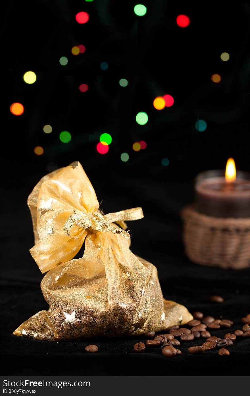 Golden christmas sack with the coffee beans and lightning candle. Golden christmas sack with the coffee beans and lightning candle