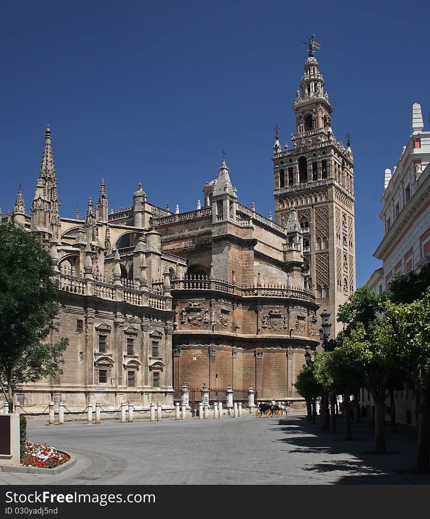 View at the largest gothic church in the world and its bell tower - Giralda, one of the characteristic symbols of Sevilla (Spain). View at the largest gothic church in the world and its bell tower - Giralda, one of the characteristic symbols of Sevilla (Spain).