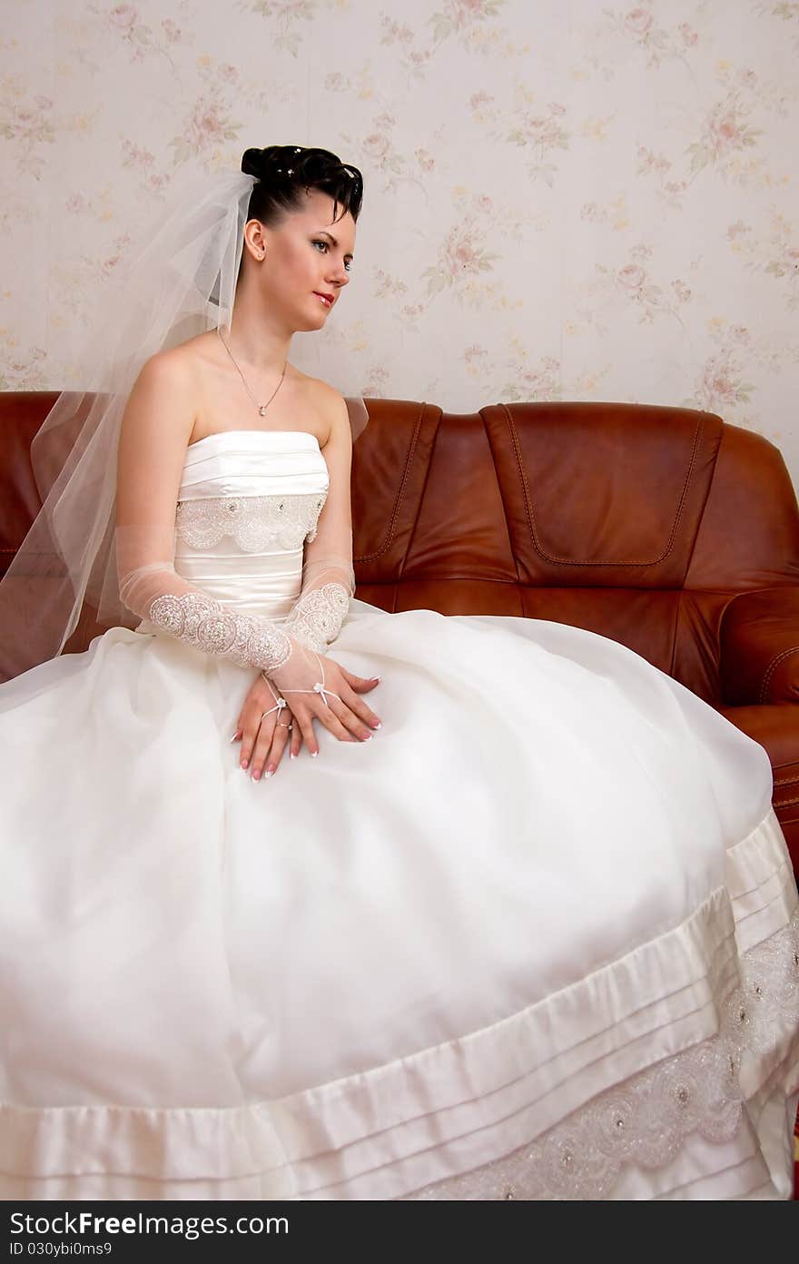 Bride sits on a leather couch.