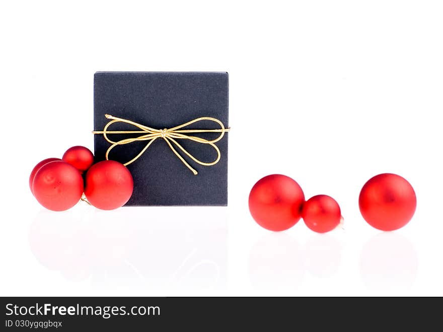 Black gift box with a gold ribbon beside red Christmas balls. Black gift box with a gold ribbon beside red Christmas balls.