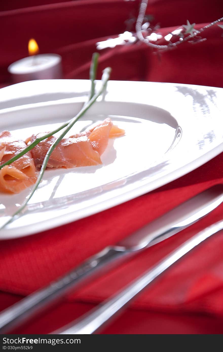 Smoked salmon with chives for Christmas, on a red-decorated table. Smoked salmon with chives for Christmas, on a red-decorated table