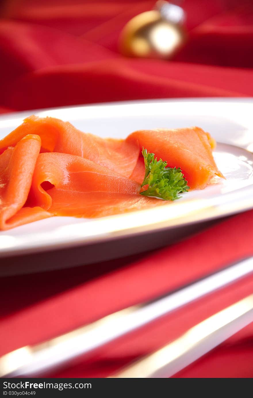 Smoked salmon with parsley for Christmas, on a red-decorated table. Smoked salmon with parsley for Christmas, on a red-decorated table