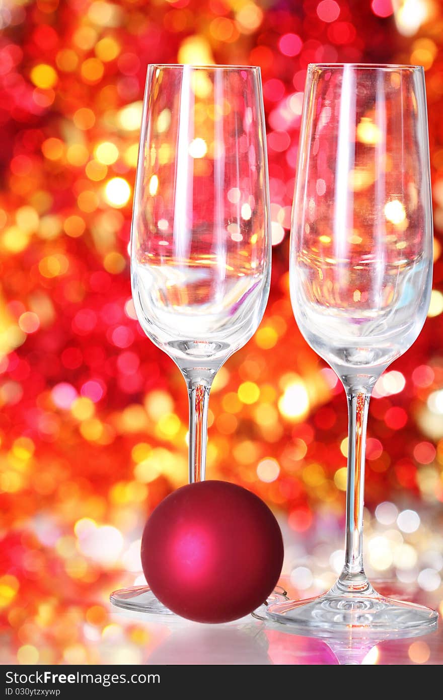 Two empty glasses and red ball decoration for champagne on the blurred background