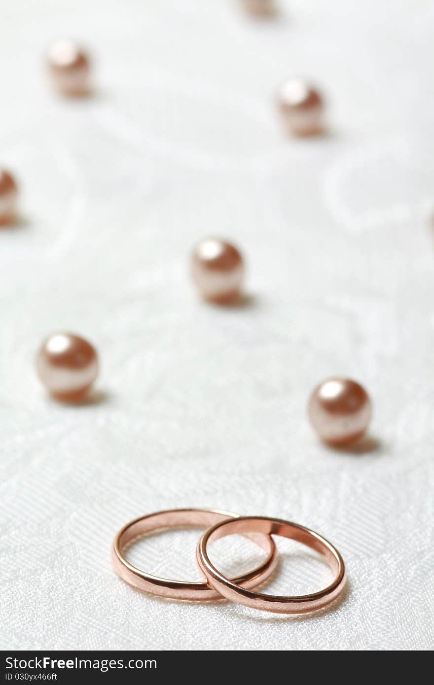 Wedding rings on lace light background with pearls