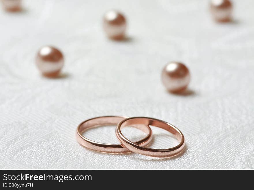 Wedding rings on lace background with pearls