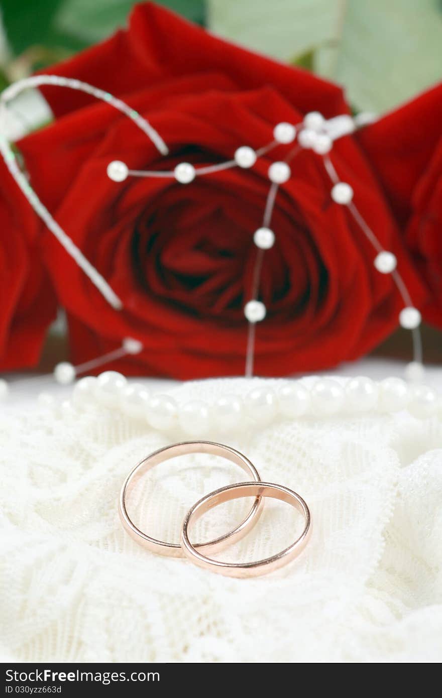 Wedding rings on lace against red rose