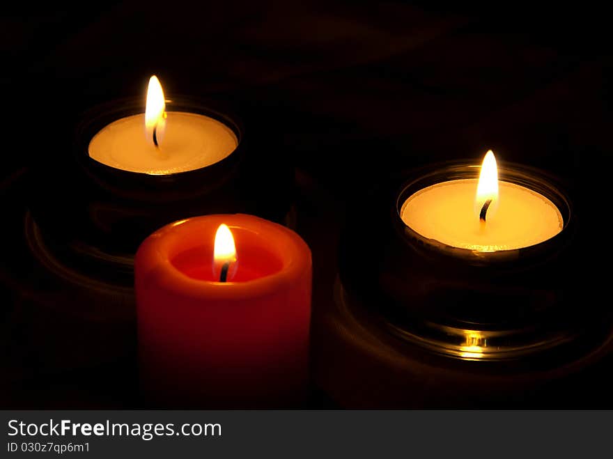 Two white and one red candle burning in the dark. Two white and one red candle burning in the dark