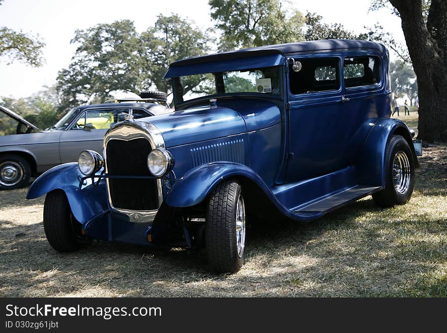 A classic blue model T parked under a shade tree near the beach at the 2010 cruisin the coast