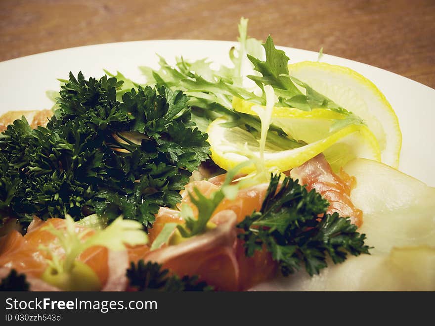 Appetizer made of meat and fish served with salad on the round plate