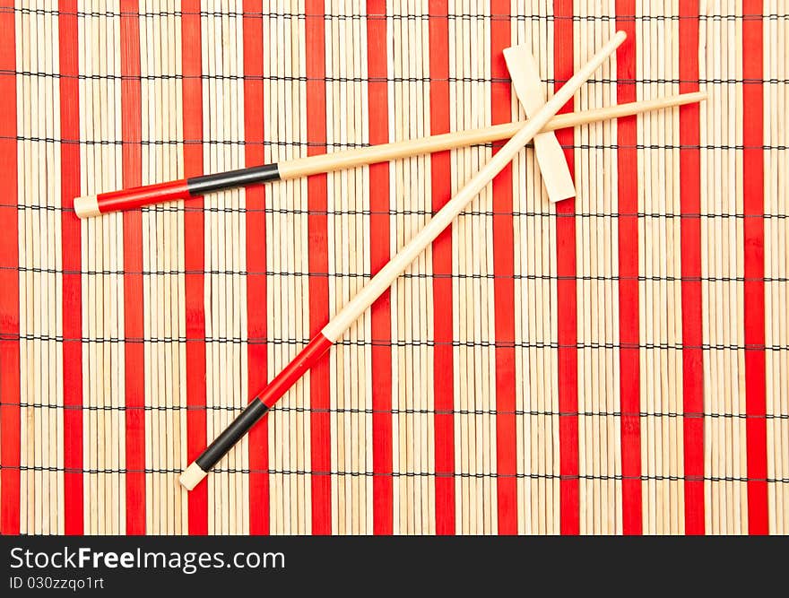 Red and black sticks for sushi on bamboo background