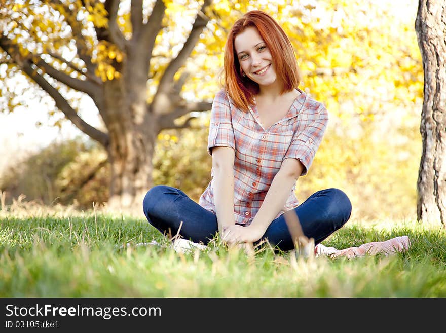 Portrait of red-haired girl in the autumn park. Outdoor shot.