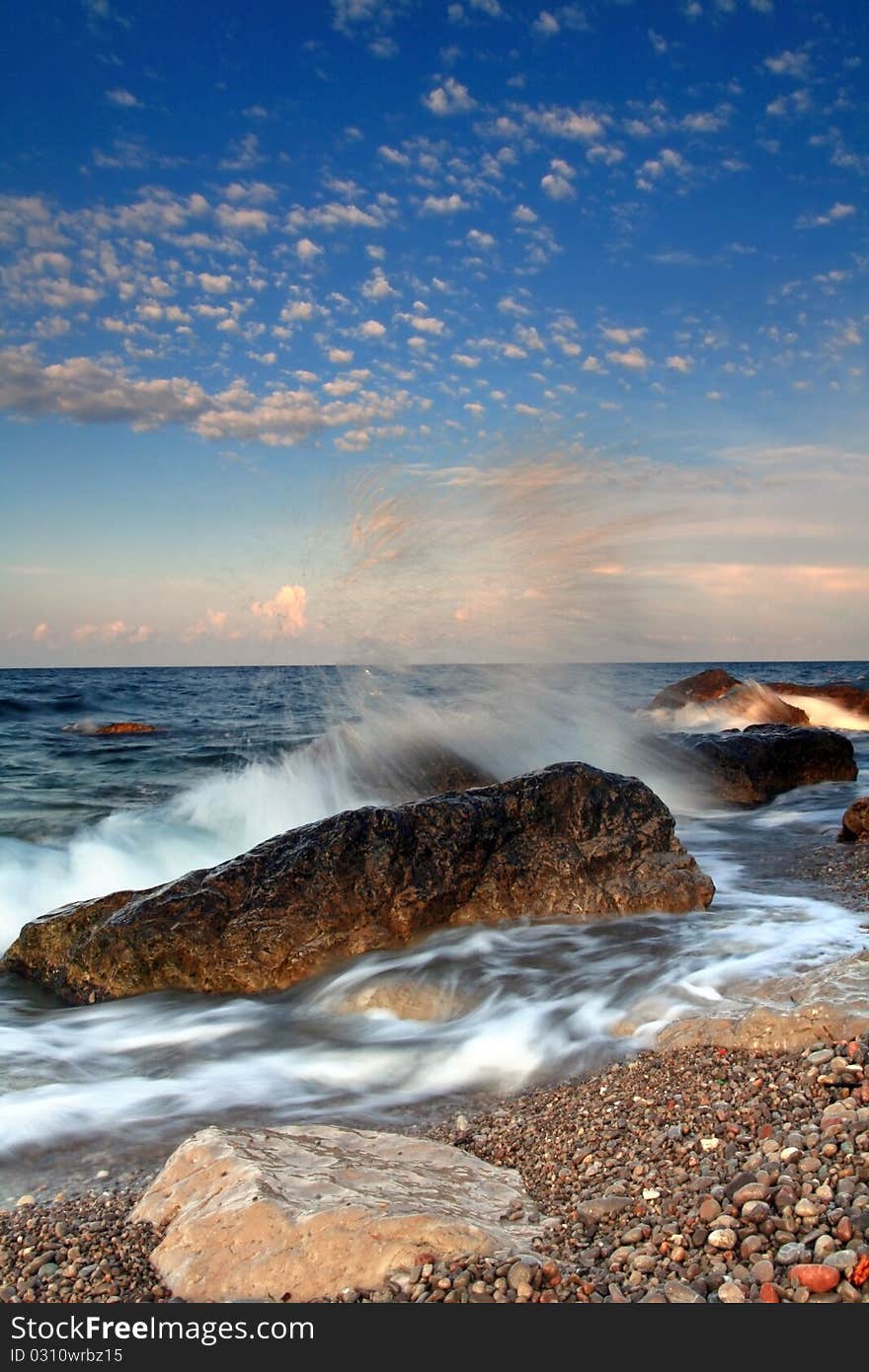 Storm waves crash on a rock in the early morning on the ocean coast. Storm waves crash on a rock in the early morning on the ocean coast