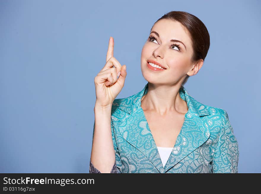 Portrait of a beautiful woman pointing at copyspace isolated on blue background