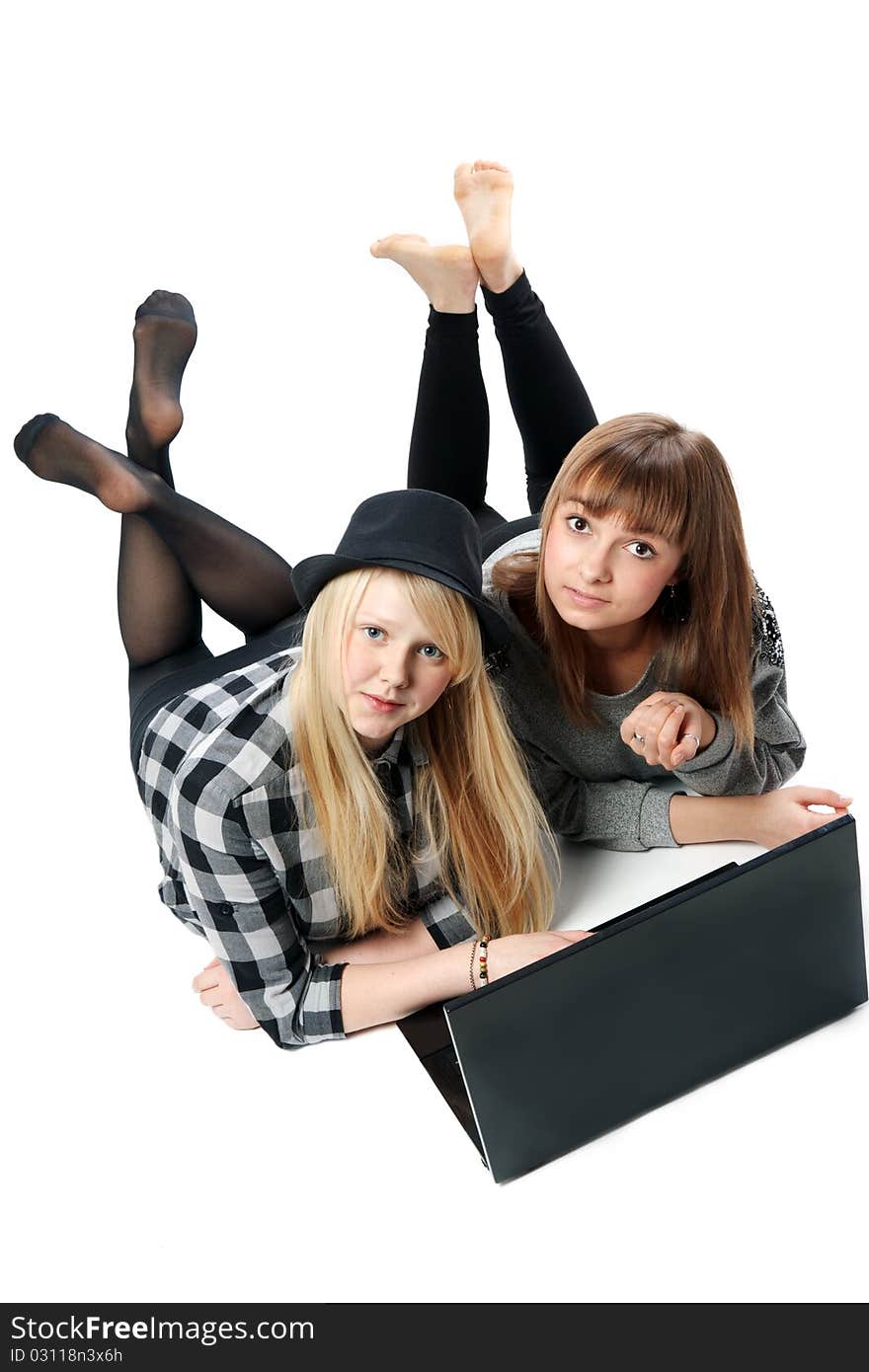 Two girls lies with computer on white background