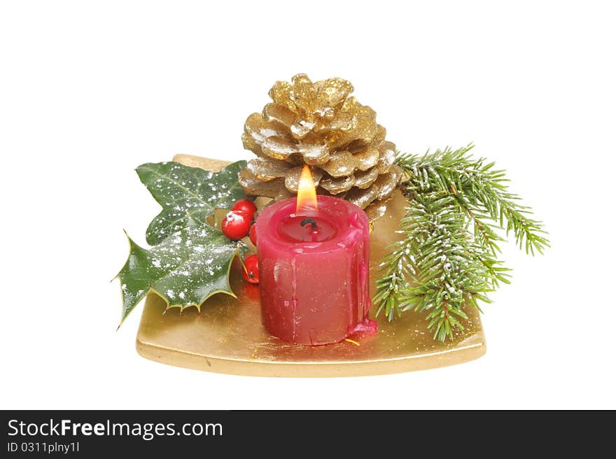 Christmas table decoration snow dusted seasonal foliage with a burning candle on a gold dish